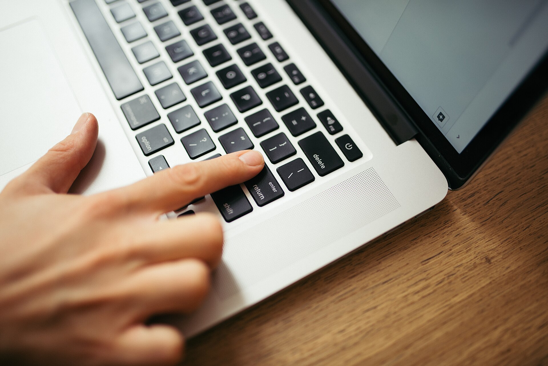 A hand typing on a laptop keyboard